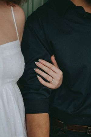Close-up of wedding ring and formal attire showing romantic embrace.