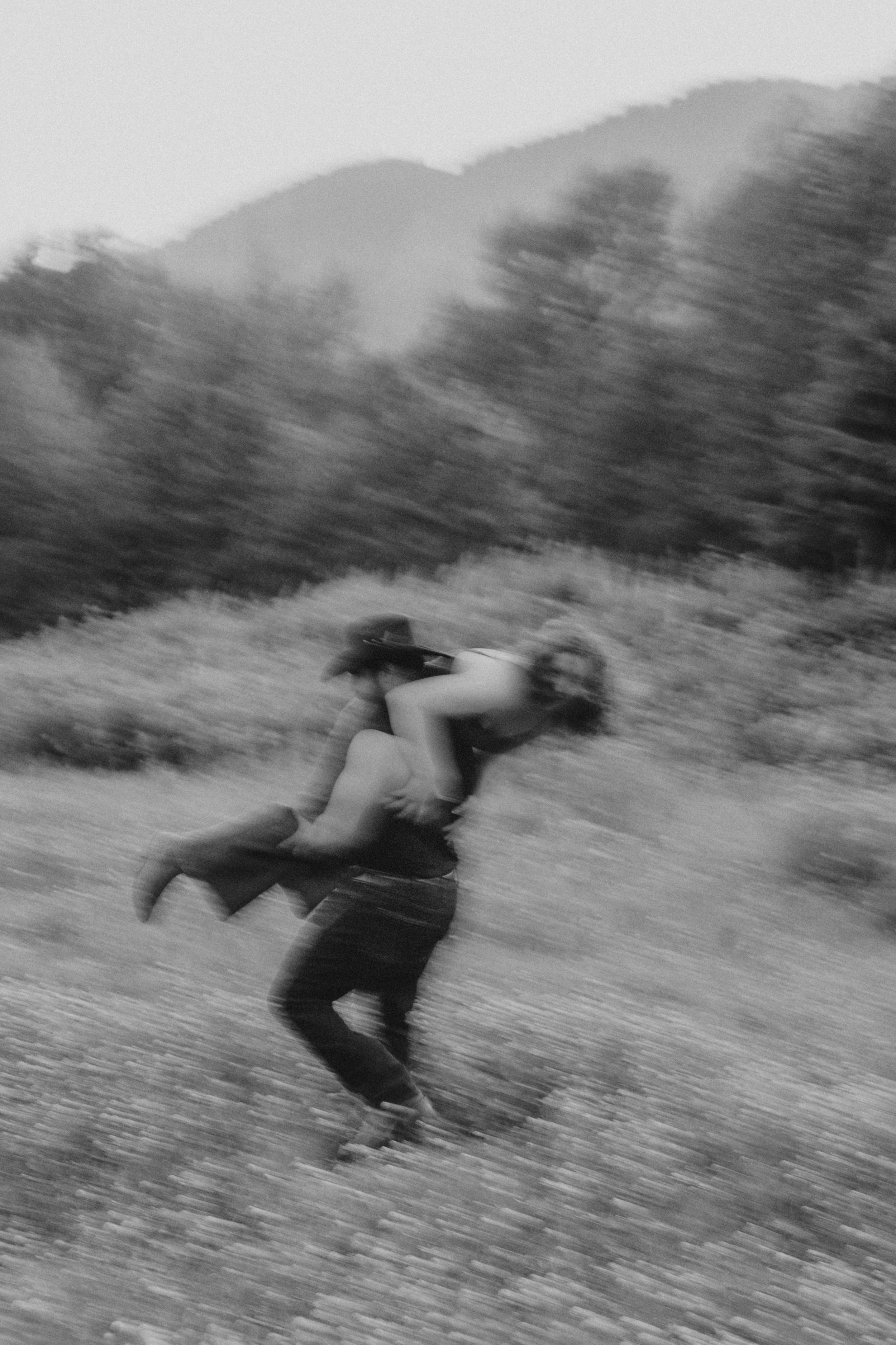 Motion-blurred romantic spin capture in black and white against mountain landscape.