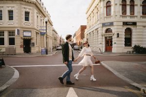 Playful couple dancing in intersection of historic city street.