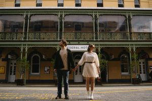 Couple standing in front of historic building with ornate green iron balconies.