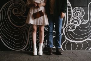 Close-up of couple's feet against wall with artistic spiral pattern.