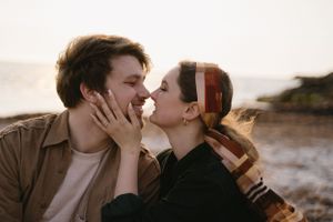 Romantic couple sharing an intimate kiss at golden hour by the ocean.