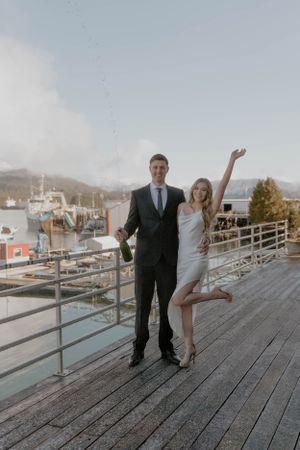A couple poses together on a wooden dock overlooking a harbor on their wedding day.