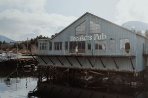 Exterior view of Breakers Pub, a white waterfront restaurant building.