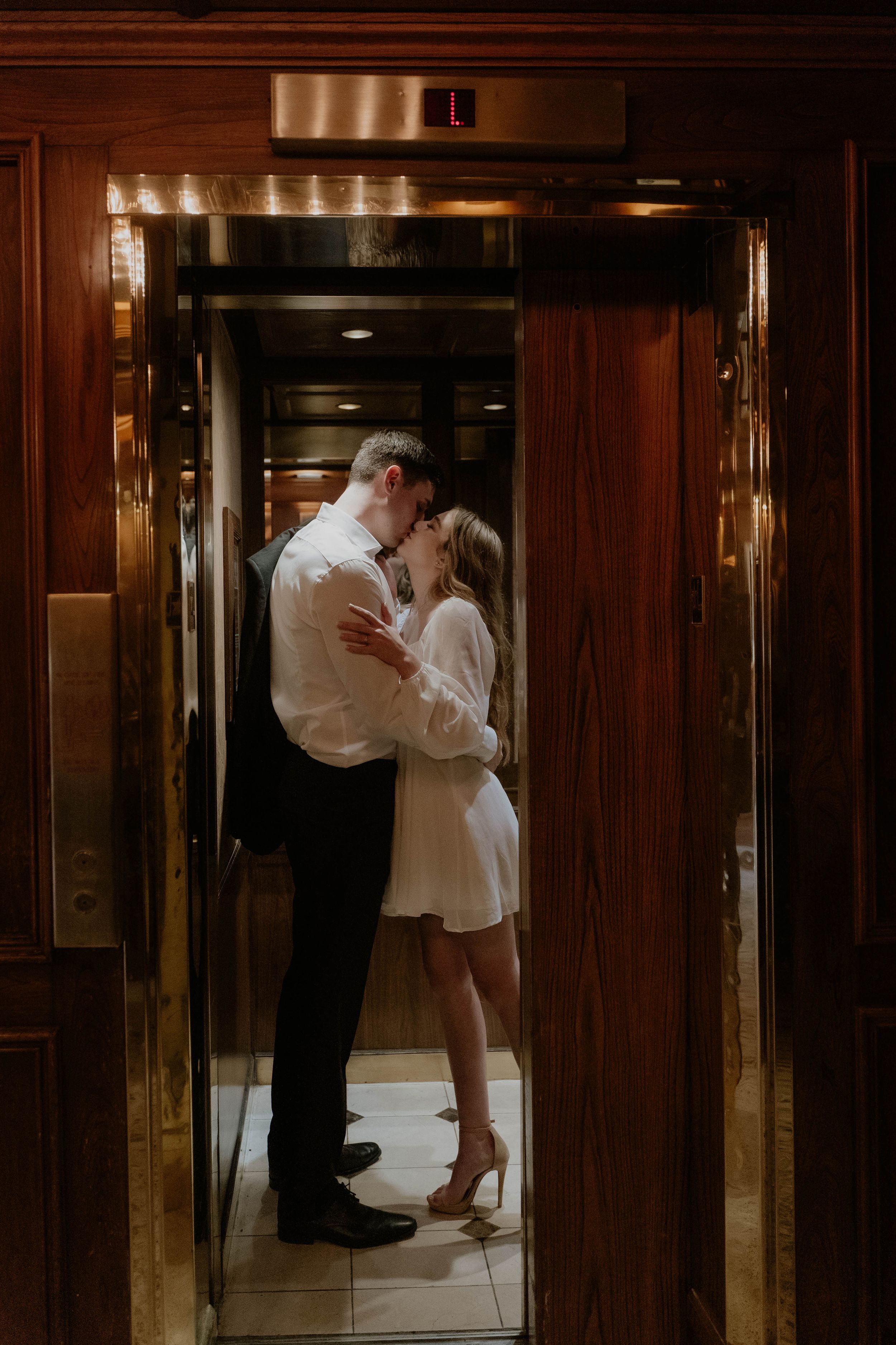 Romantic couple sharing an intimate moment in an elegant elevator.