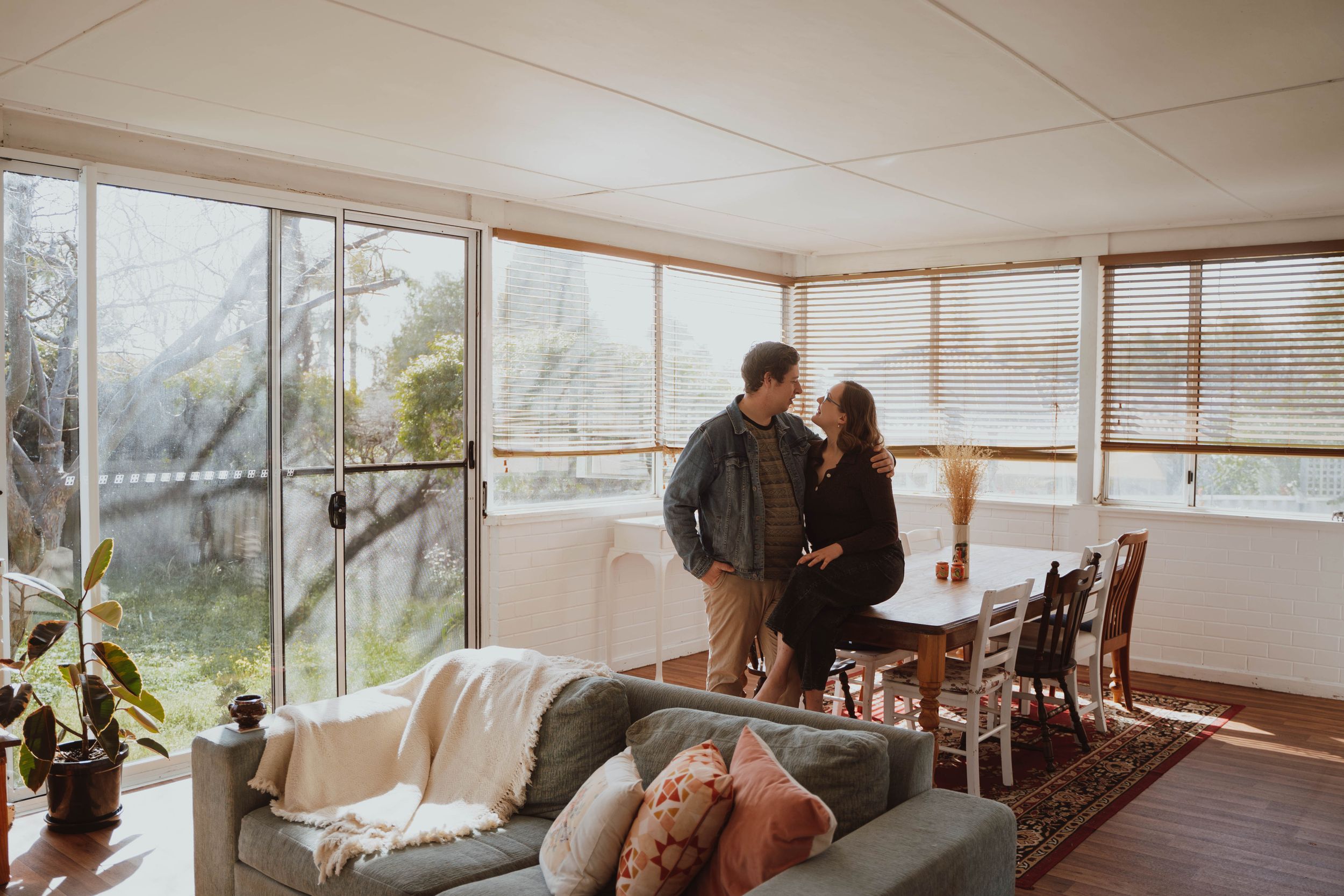 A bright sunroom with large windows overlooking nature and furniture creating an inviting atmosphere.