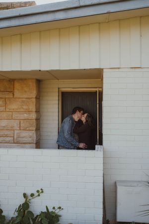 A tender moment shared between two people in a white brick doorway.