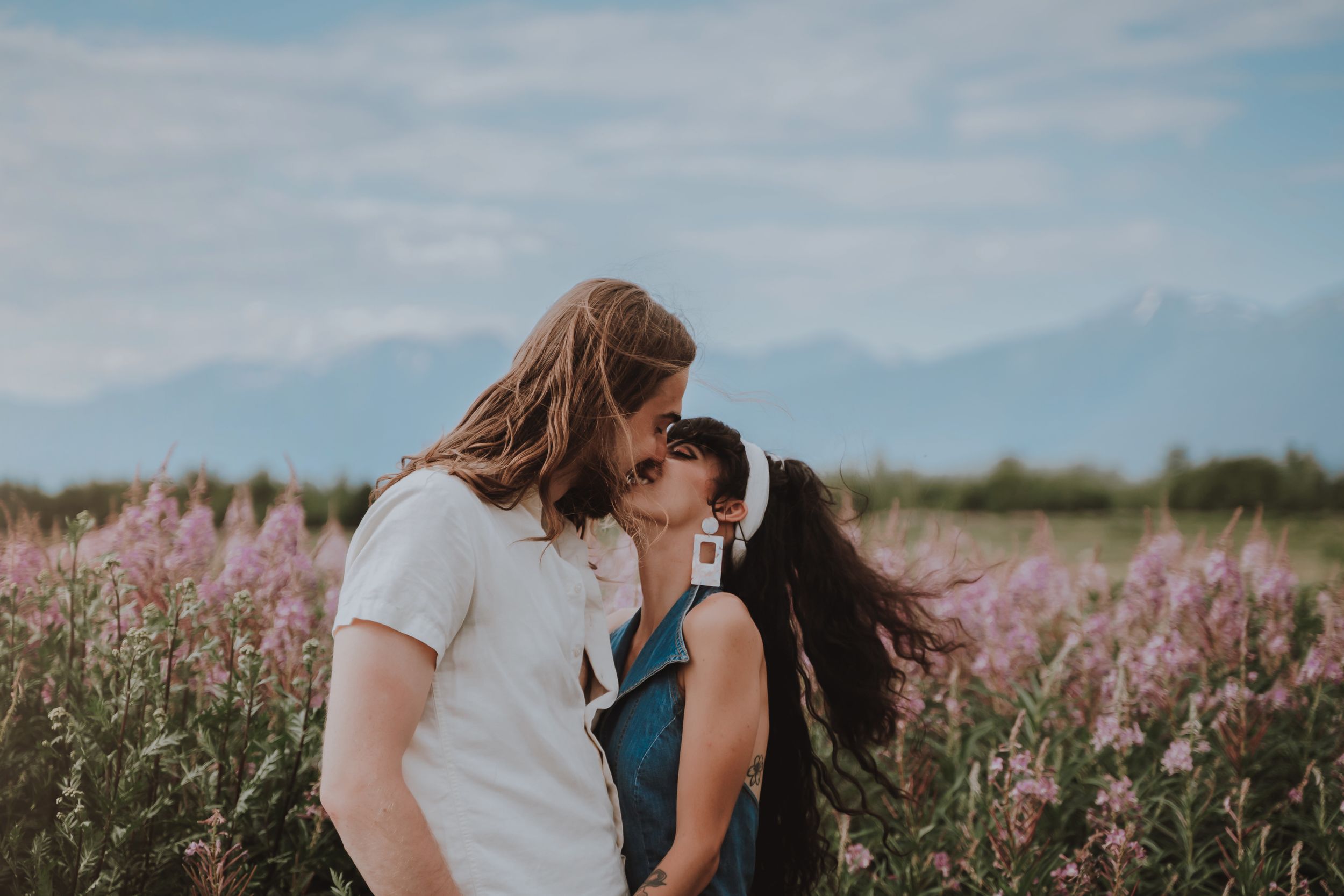 A romantic moment between two people in a field of pink wildflowers.