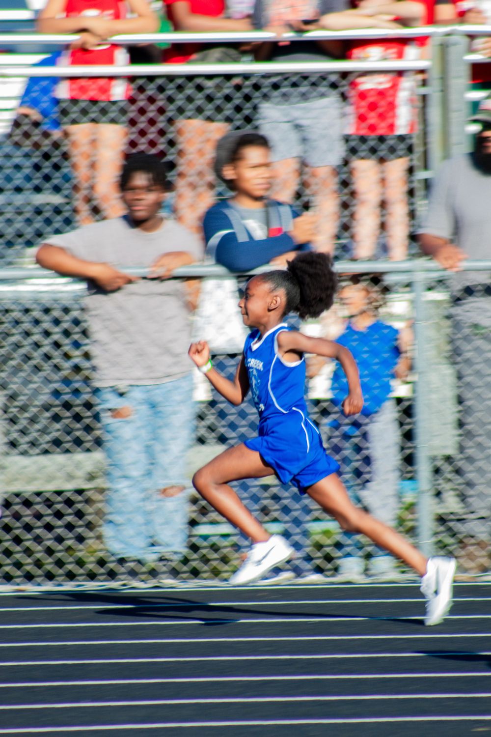 A sequence of action shots showing a sprinter in blue uniform running on an outdoor track.