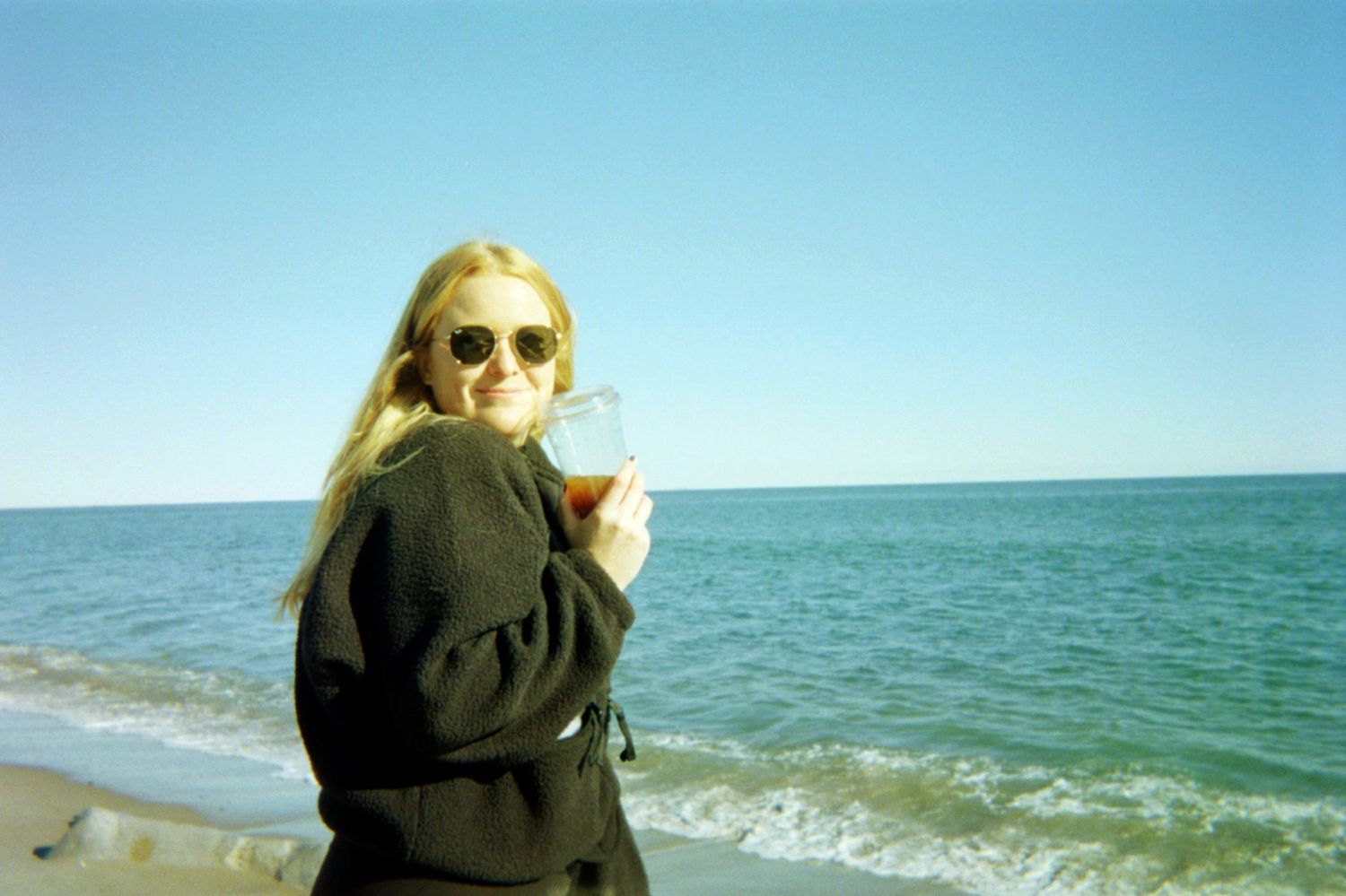 A sequence of someone walking along a sunny beach with waves crashing against the shore in the background.
