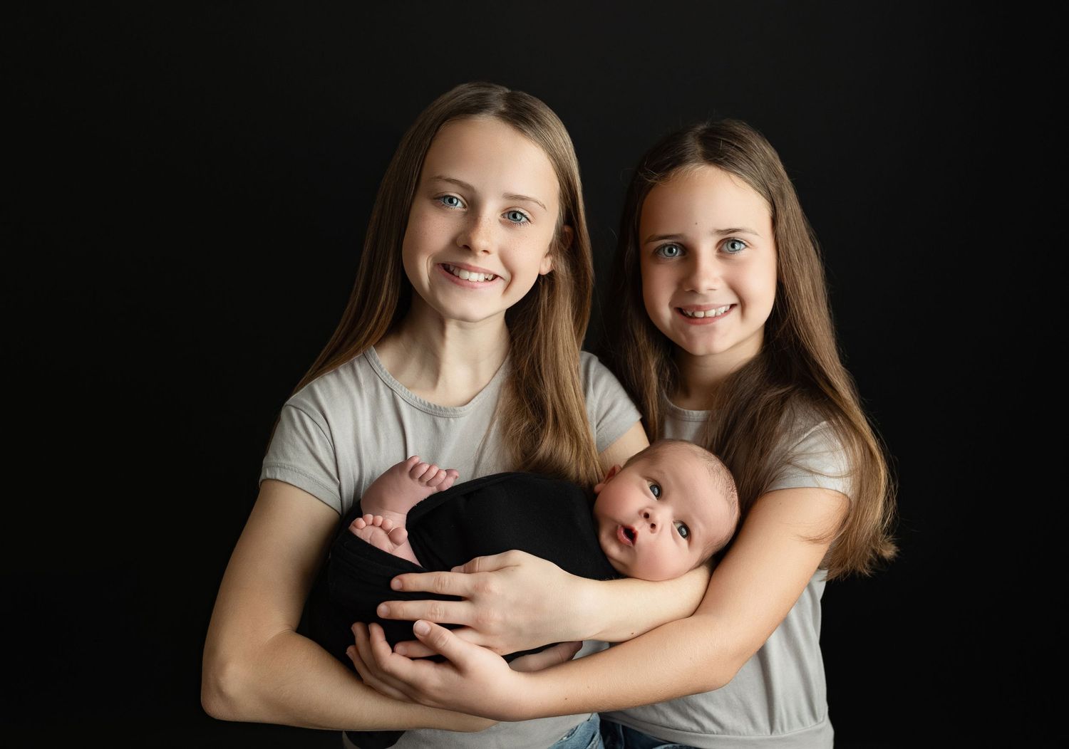 Big sisters smiling holding newborn brother. Greenville SC newborn photographer, Easley, SC newborn photographer