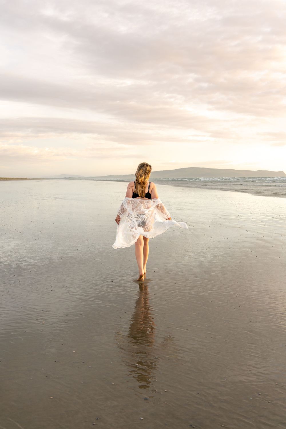 Woman walking along the sand at the beach in a robe