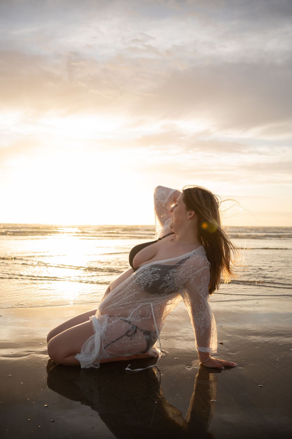 Woman sitting on the sand at the beach in a robe