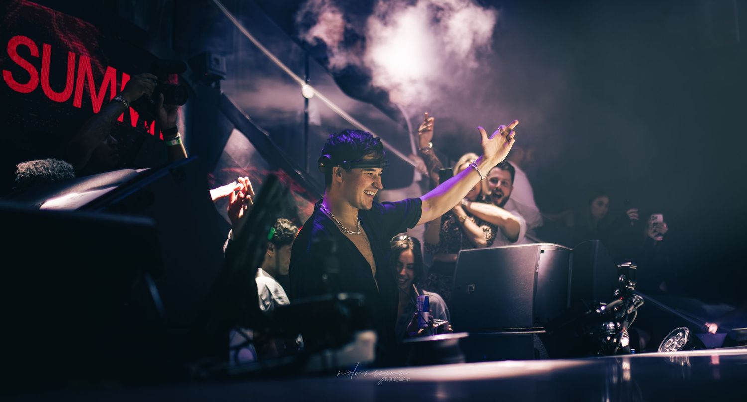 Dark concert venue with dramatic purple lighting and silhouettes on stage.