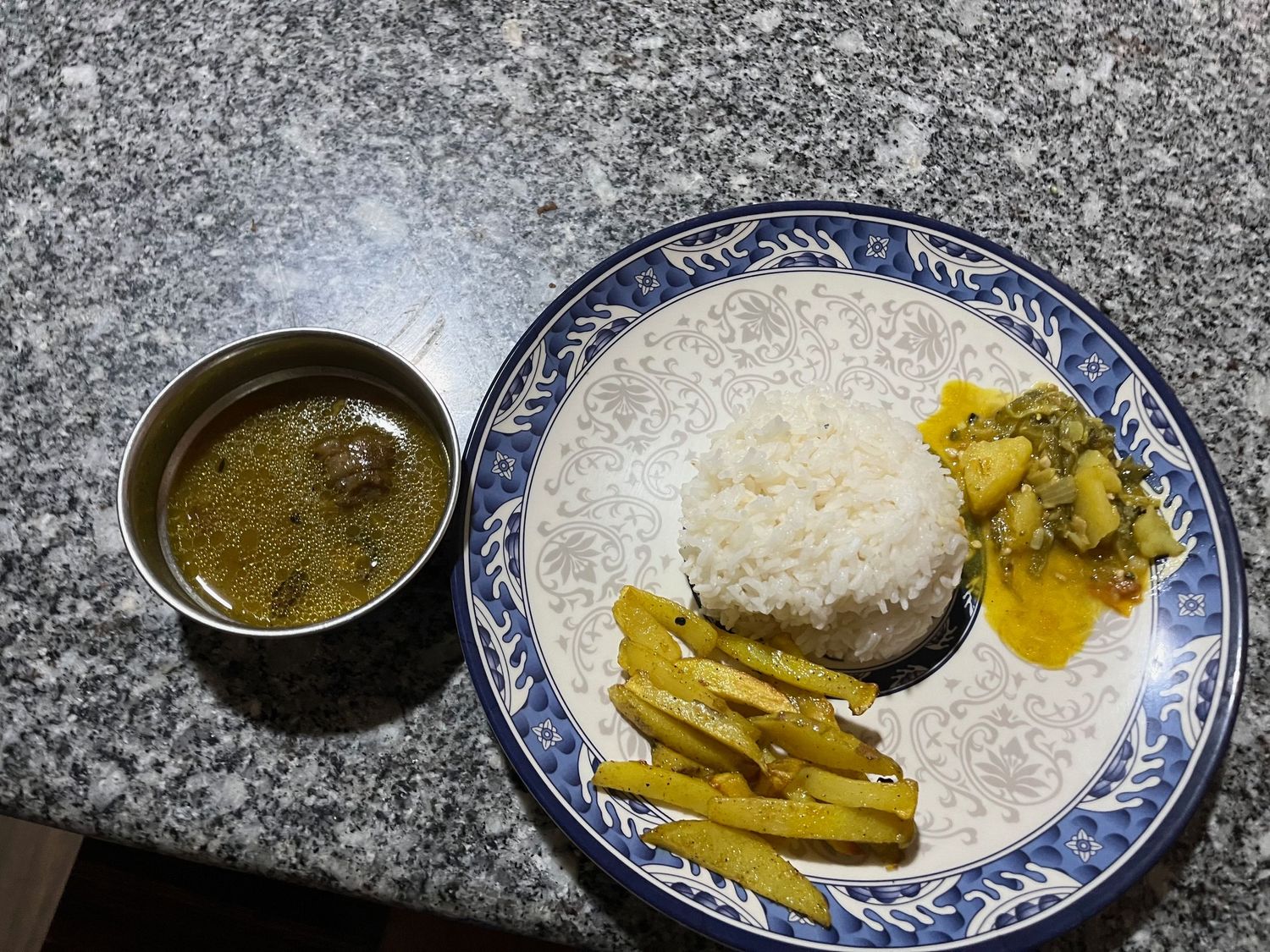 Traditional Asian meal with rice, curry, and pickled vegetables on a blue and white plate.