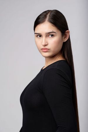 Studio portrait of someone in a black long sleeve top against a light gray background.