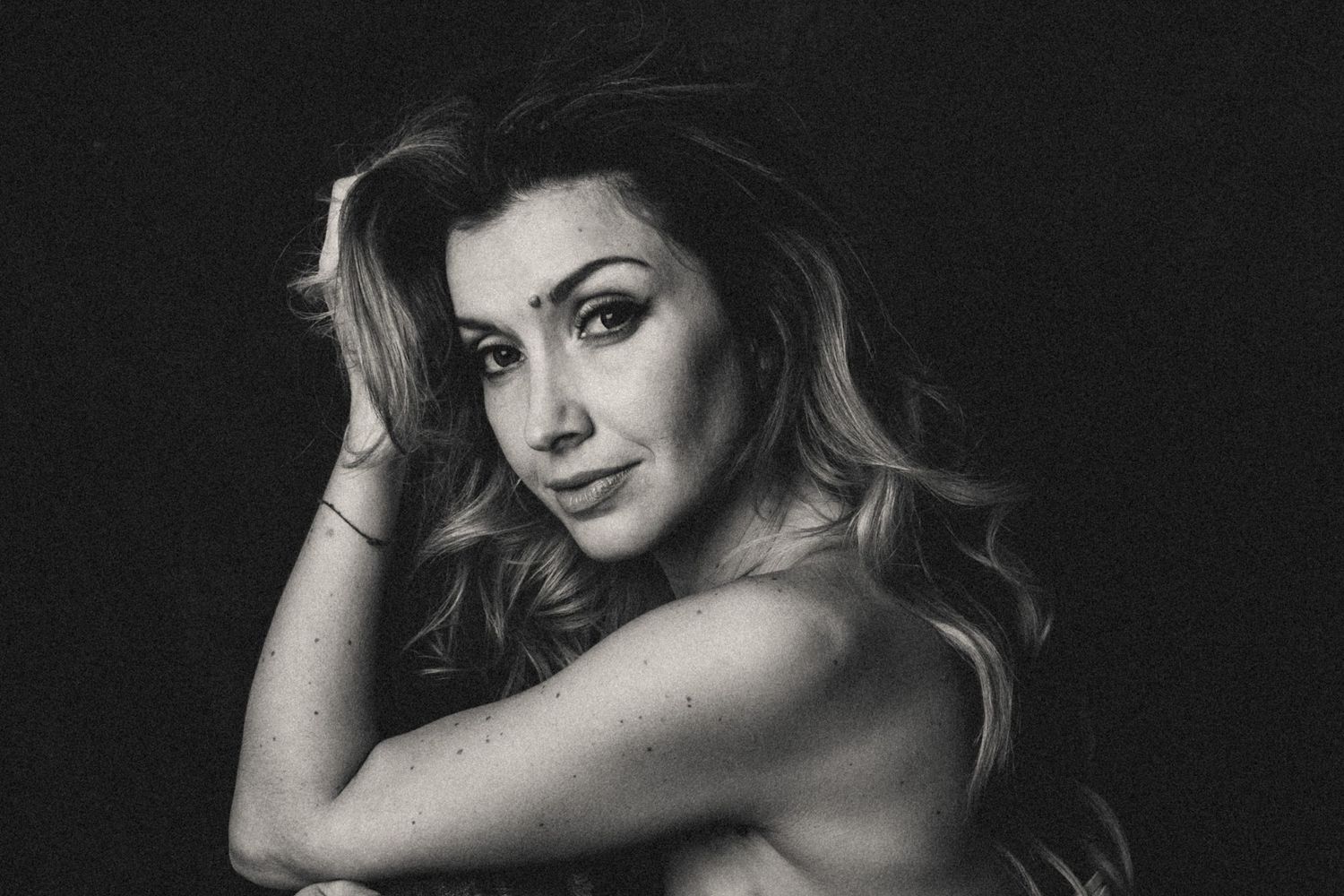 Black and white boudoir portrait of a woman posing naturally, expressing intimate emotion and self-acceptance.