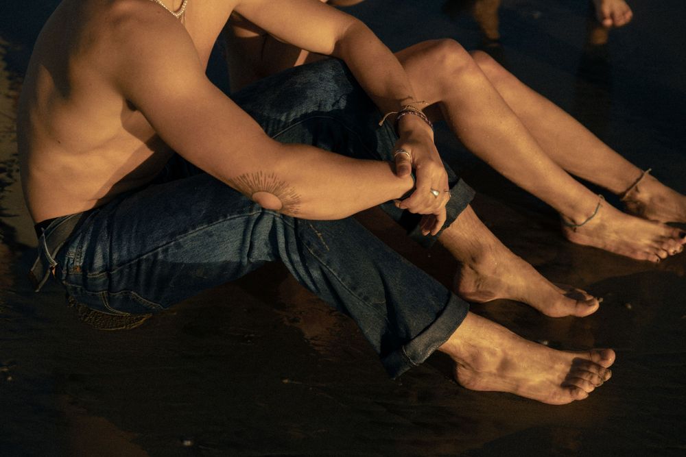 Bare feet resting on dark surface at sunset creating dramatic shadows.