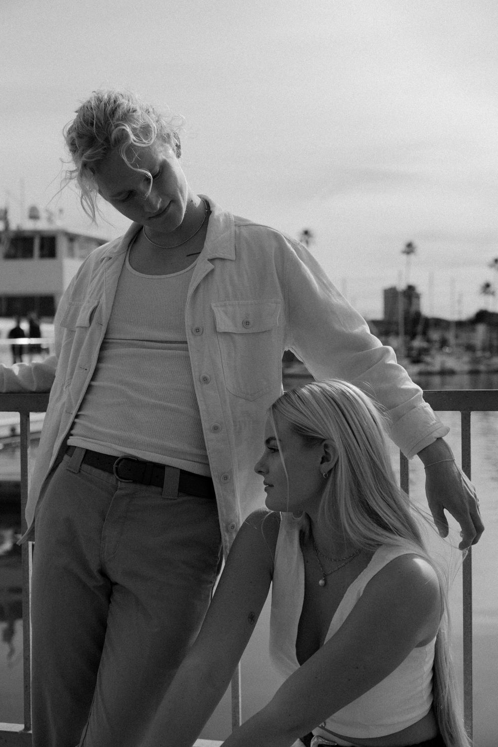 Two people in casual summer clothing standing on a marina deck.