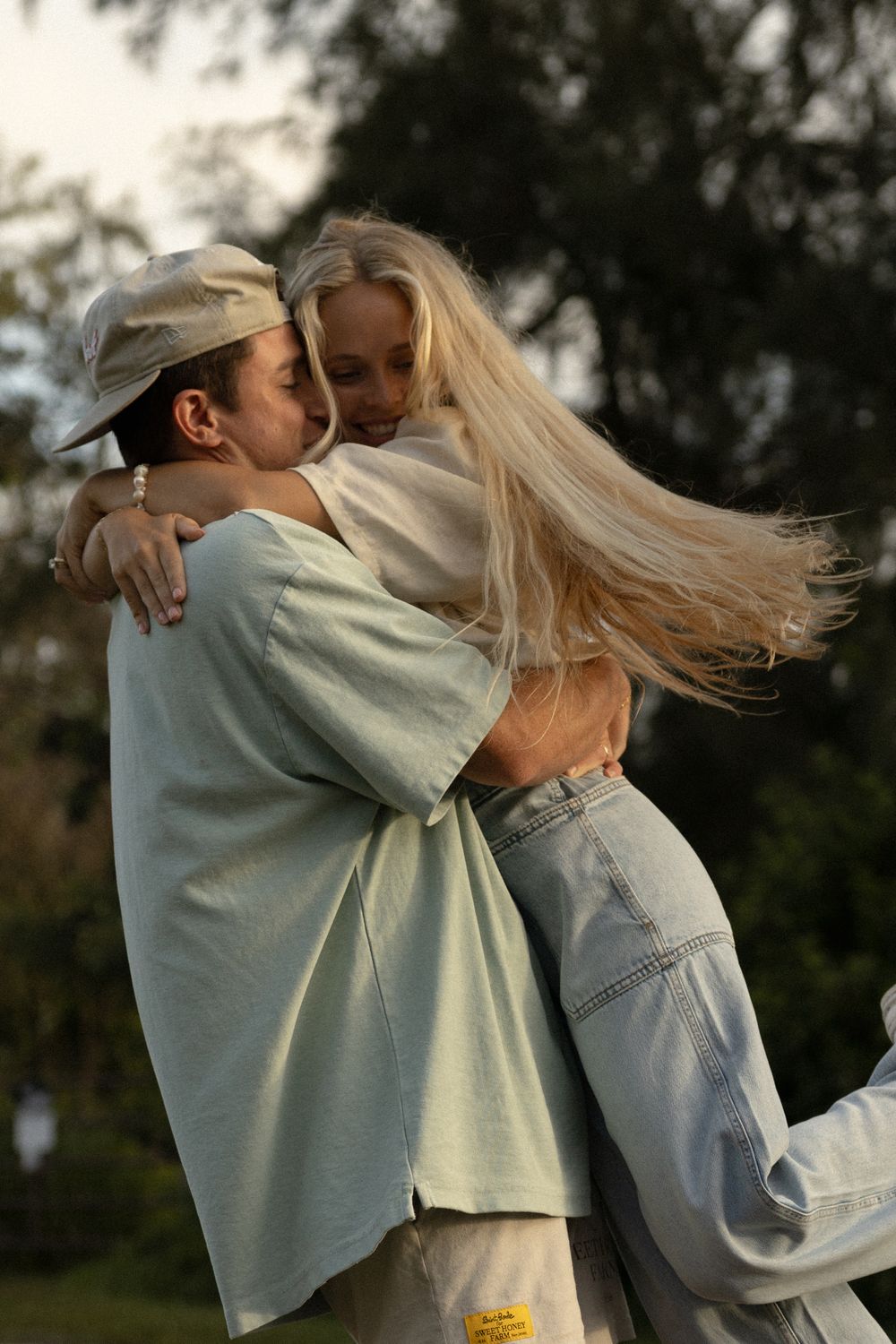 A tender moment captured between a couple as her blonde hair flows in the wind.