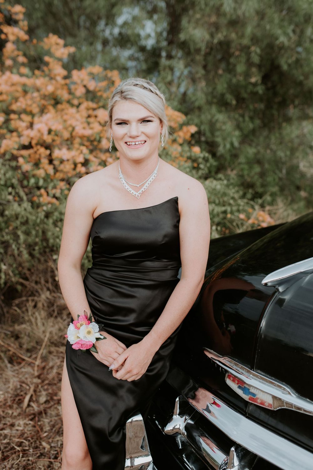 Elegant black dress against vintage car chrome bumper and autumn foliage.