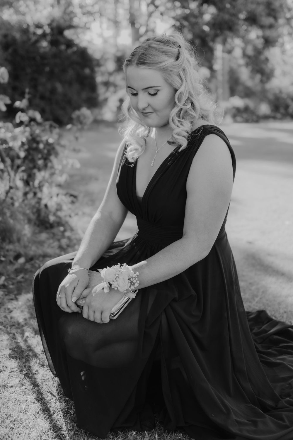 Black and white photo of person in formal dress seated in garden setting.