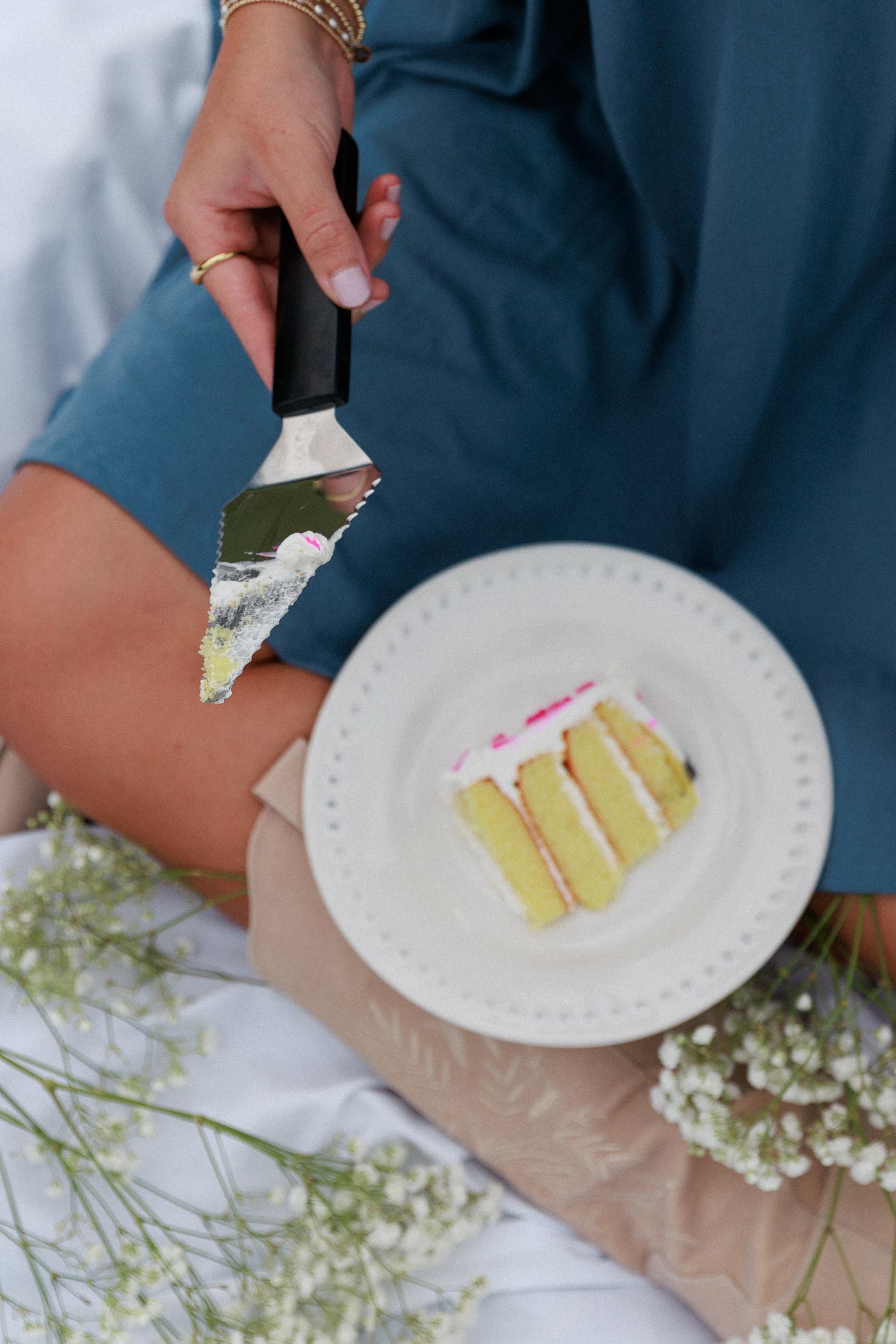 Slice of layered vanilla cake being served on white plate with baby's breath flowers.