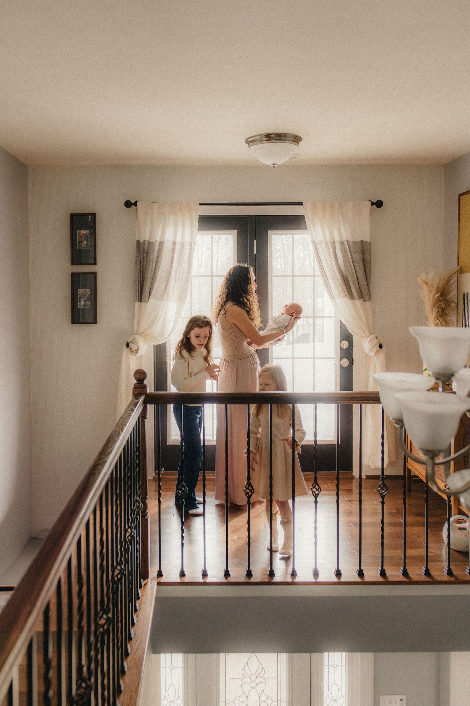 People standing by window on second floor landing with curtains and hardwood floors.