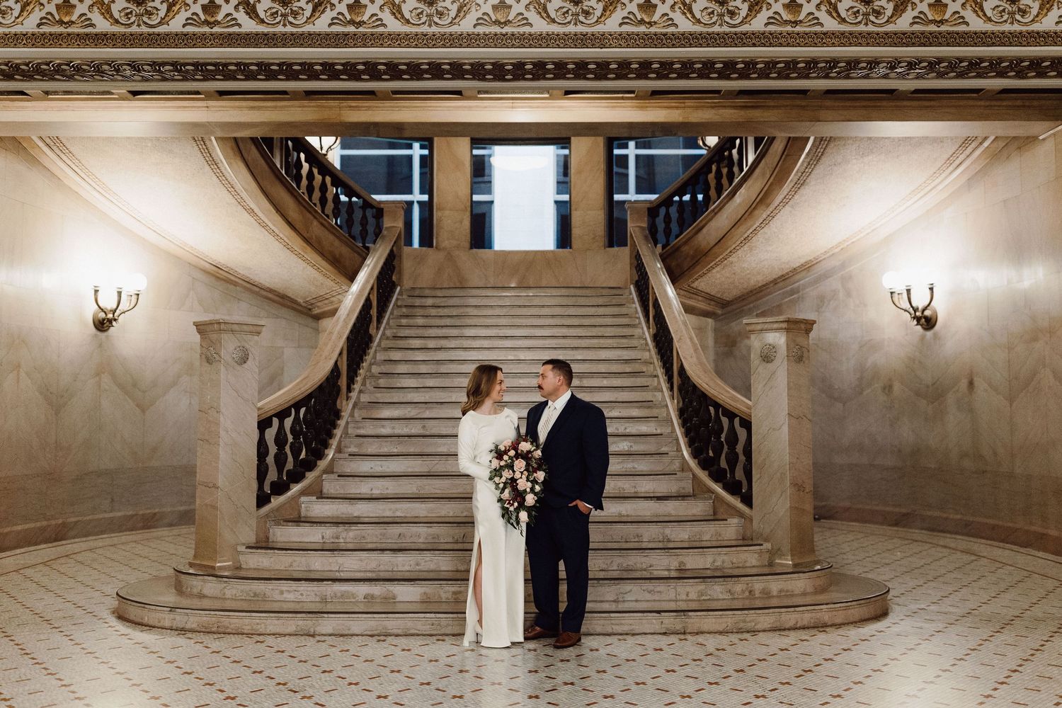 Romantic moment captured on elegant marble staircase in historic building interior.