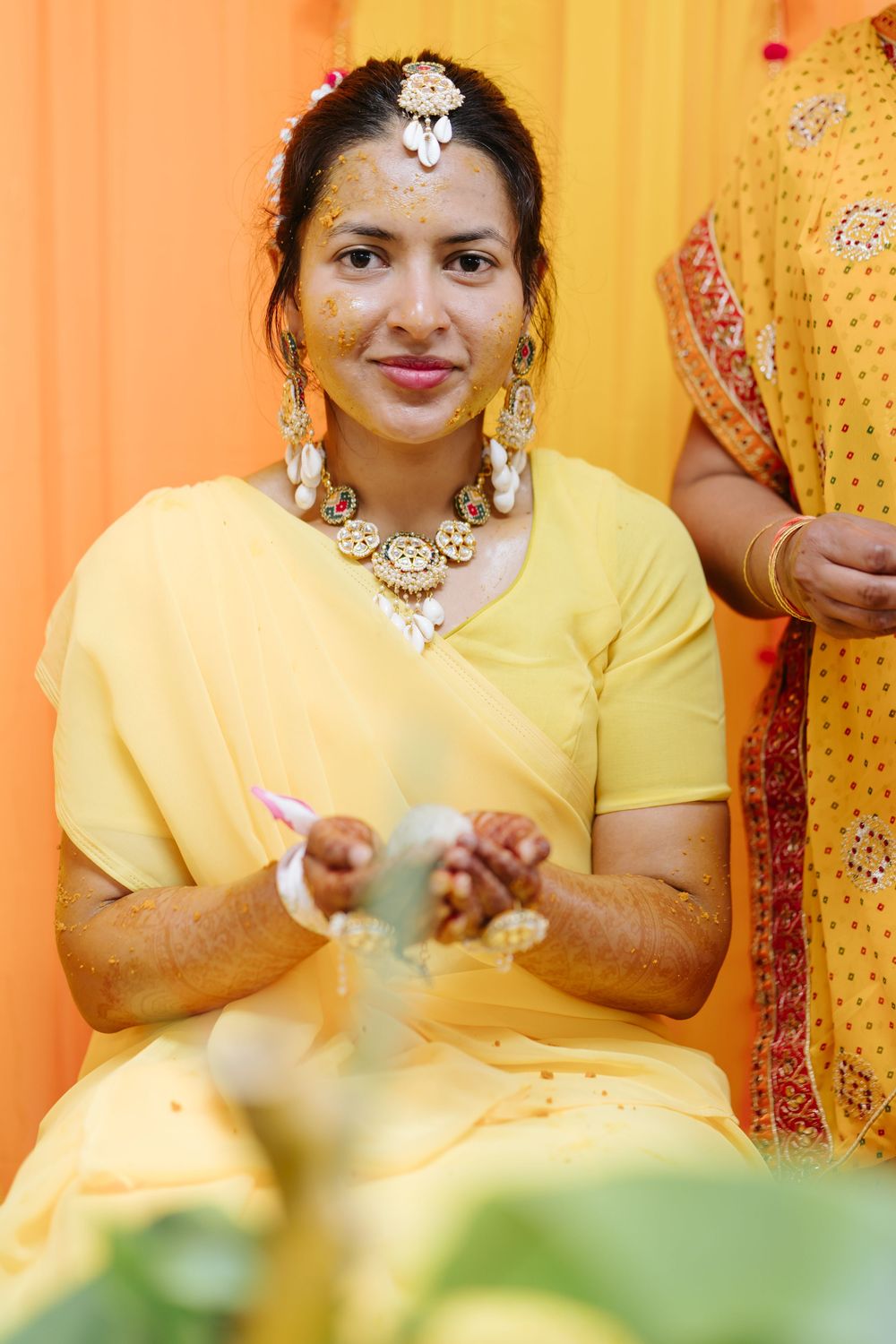 Traditional Indian wedding ceremony showing yellow-clad guests performing cultural rituals and customs.