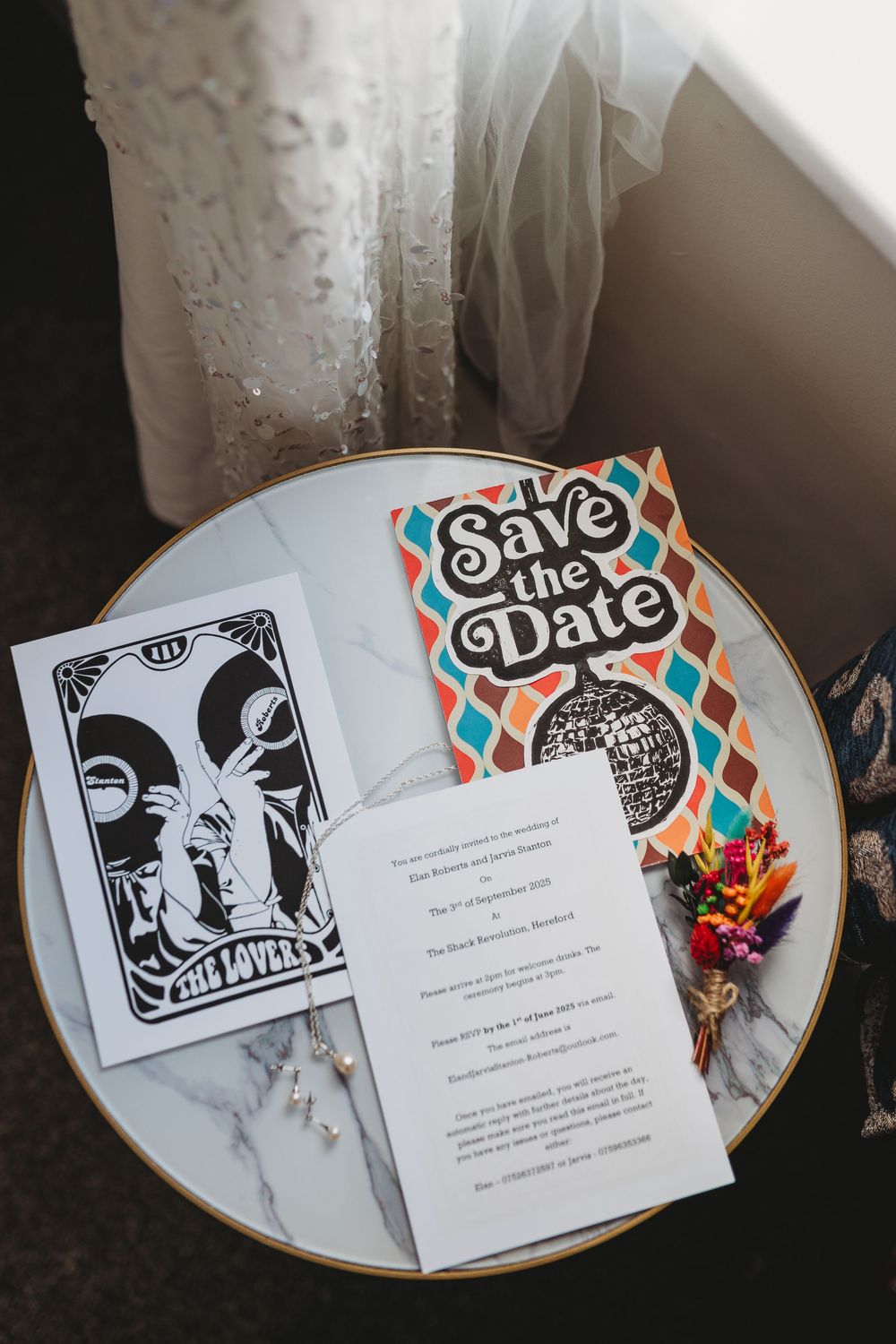 Wedding invitation suite with 'Save the Date' card and decorative elements displayed on a marble plate.