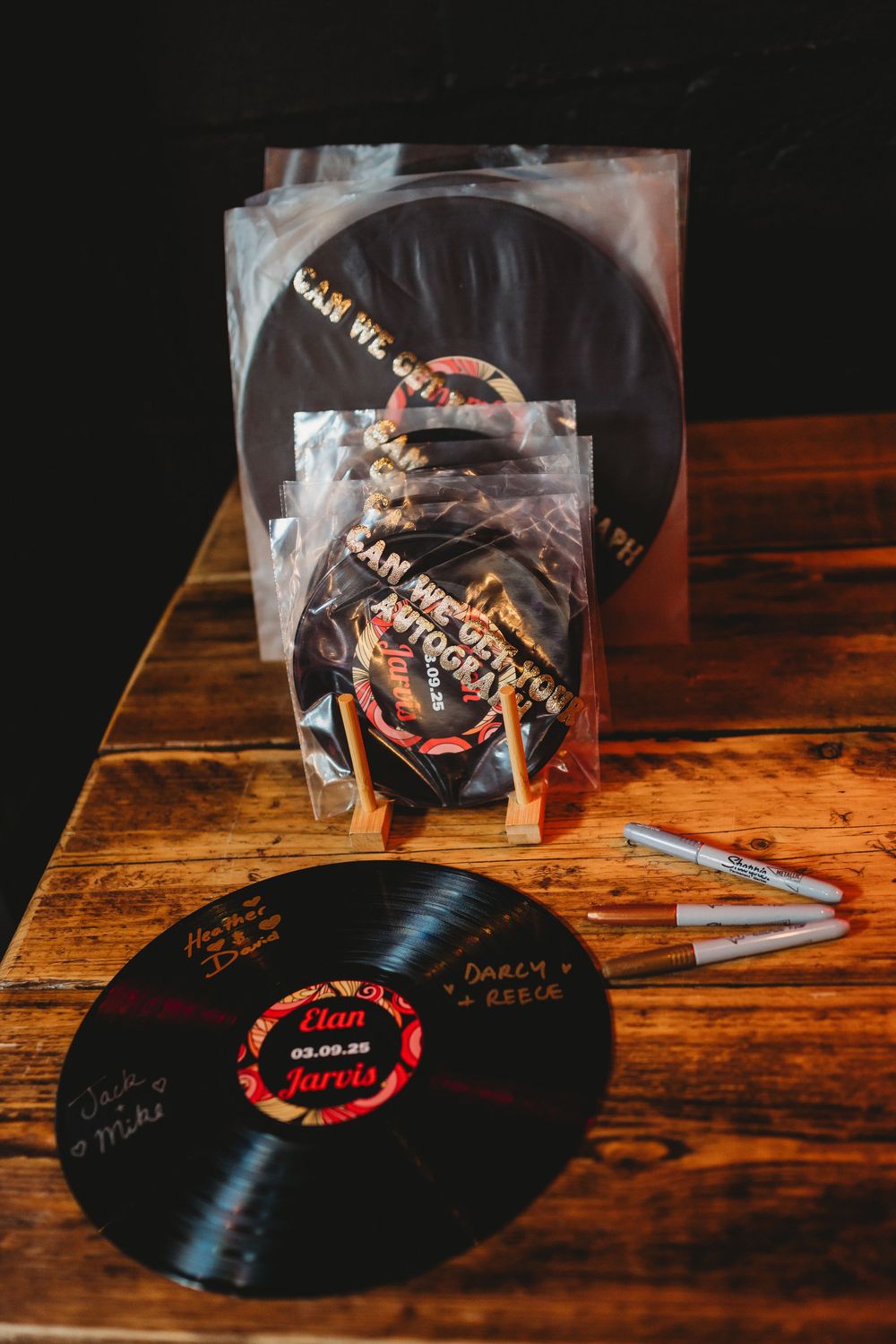 Vinyl records with signatures displayed on a rustic wooden table.