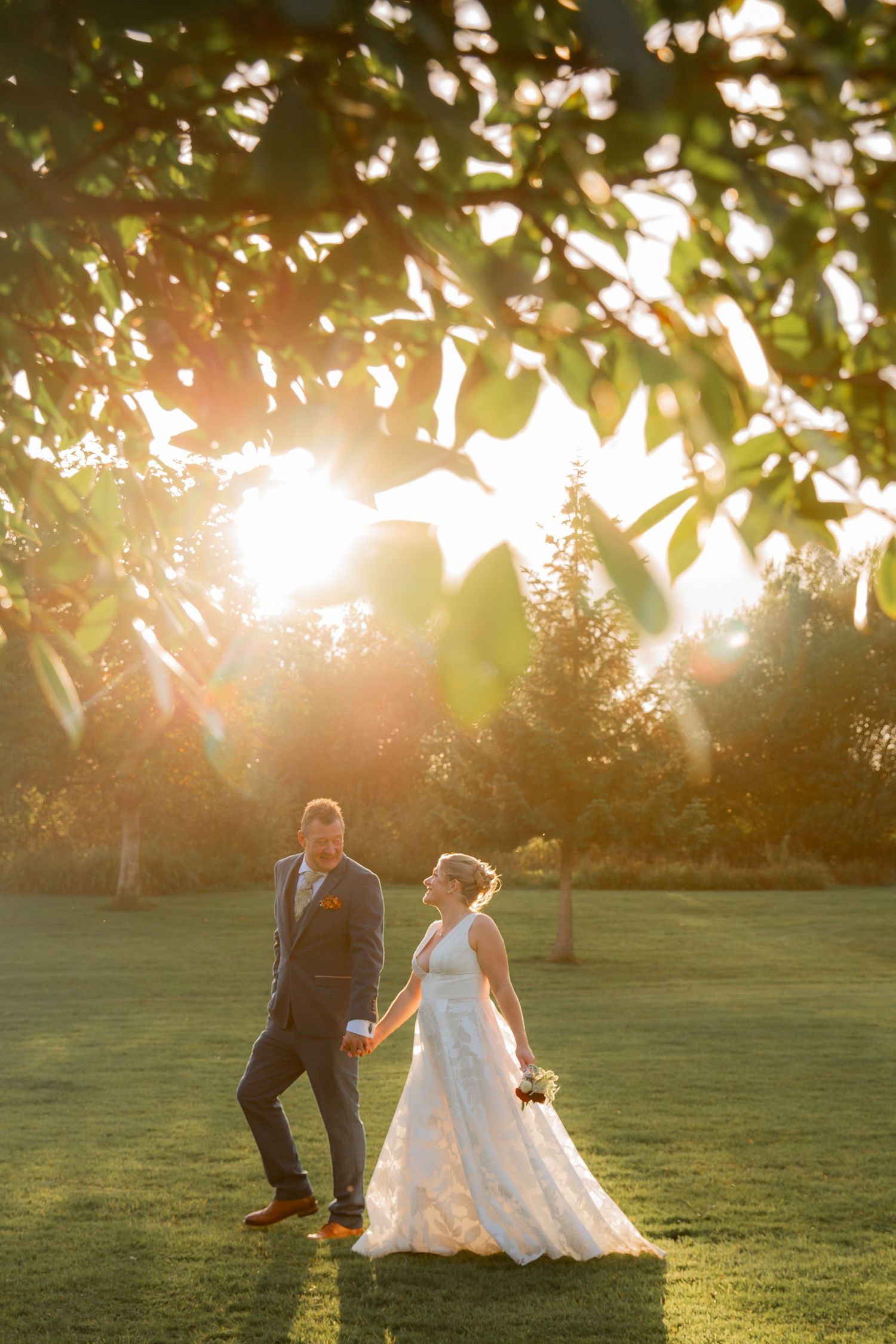 A couple dances together in a sun-drenched garden during golden hour, creating a romantic silhouette against the grass.