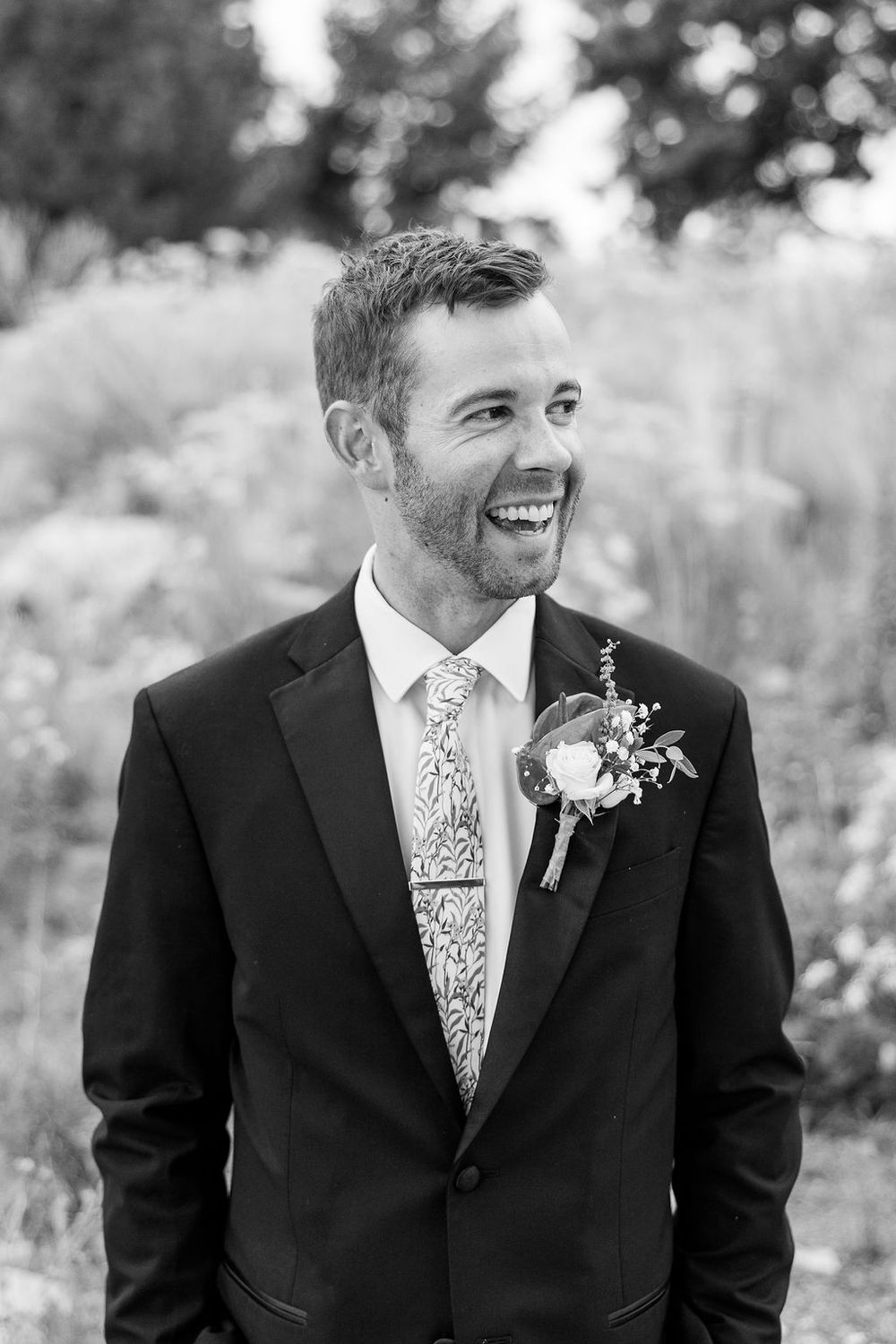 Black and white portraits showing joyful expressions in formal wedding attire with floral boutonniere.