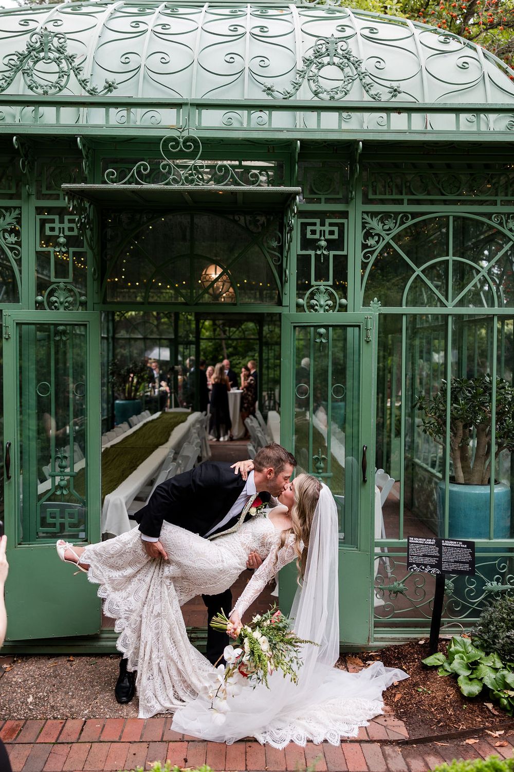 Romantic wedding photos captured in front of a vintage green conservatory with flowing white dress and elegant poses.