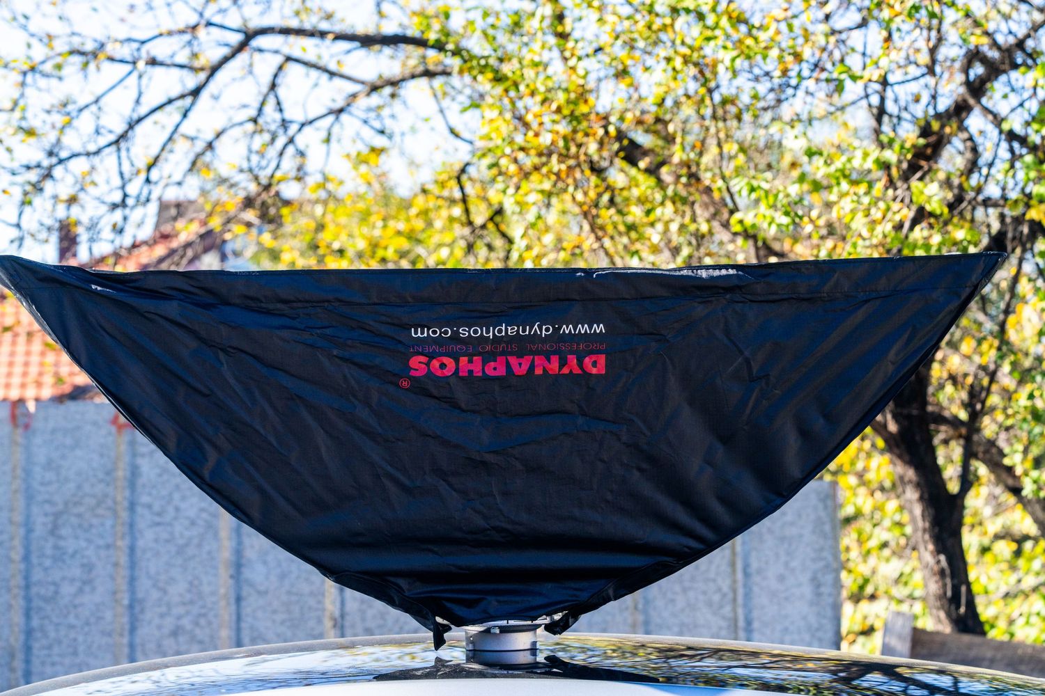 Black hammock with red Equalstram logo displayed outdoors against autumn trees and blue sky background.