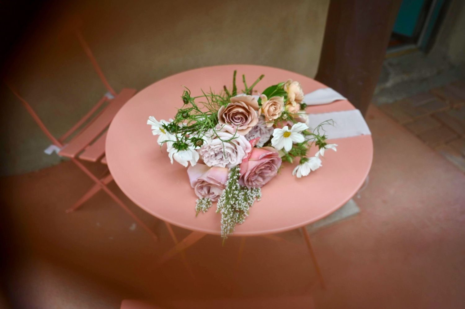 A pink table setting with white floral centerpiece and decorative arrangements at a wedding.