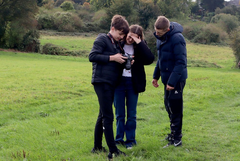 Students exploring and learning outdoors in a grassy field.