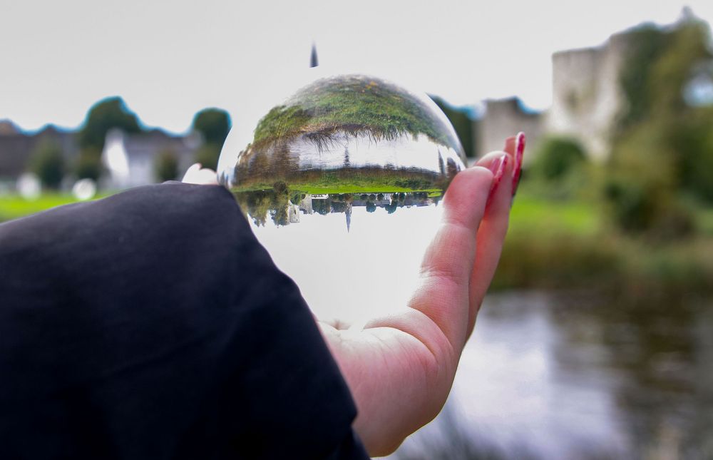 Hand reaching out over a scenic waterfront view with buildings in the distance.