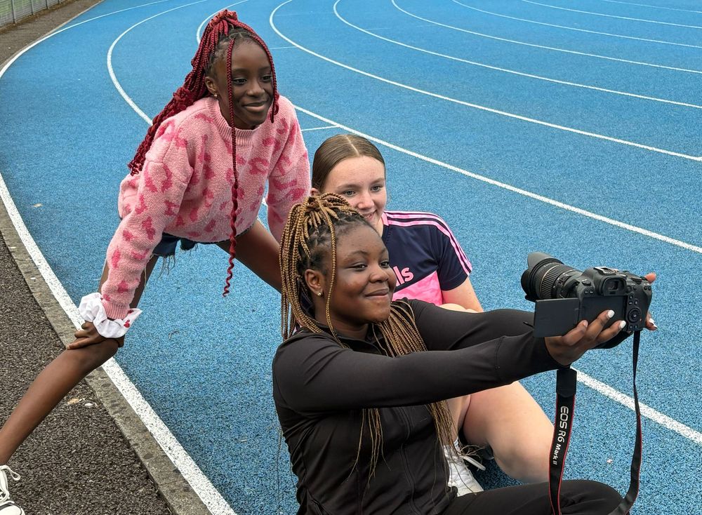 Athletes stretching and warming up on a blue running track.