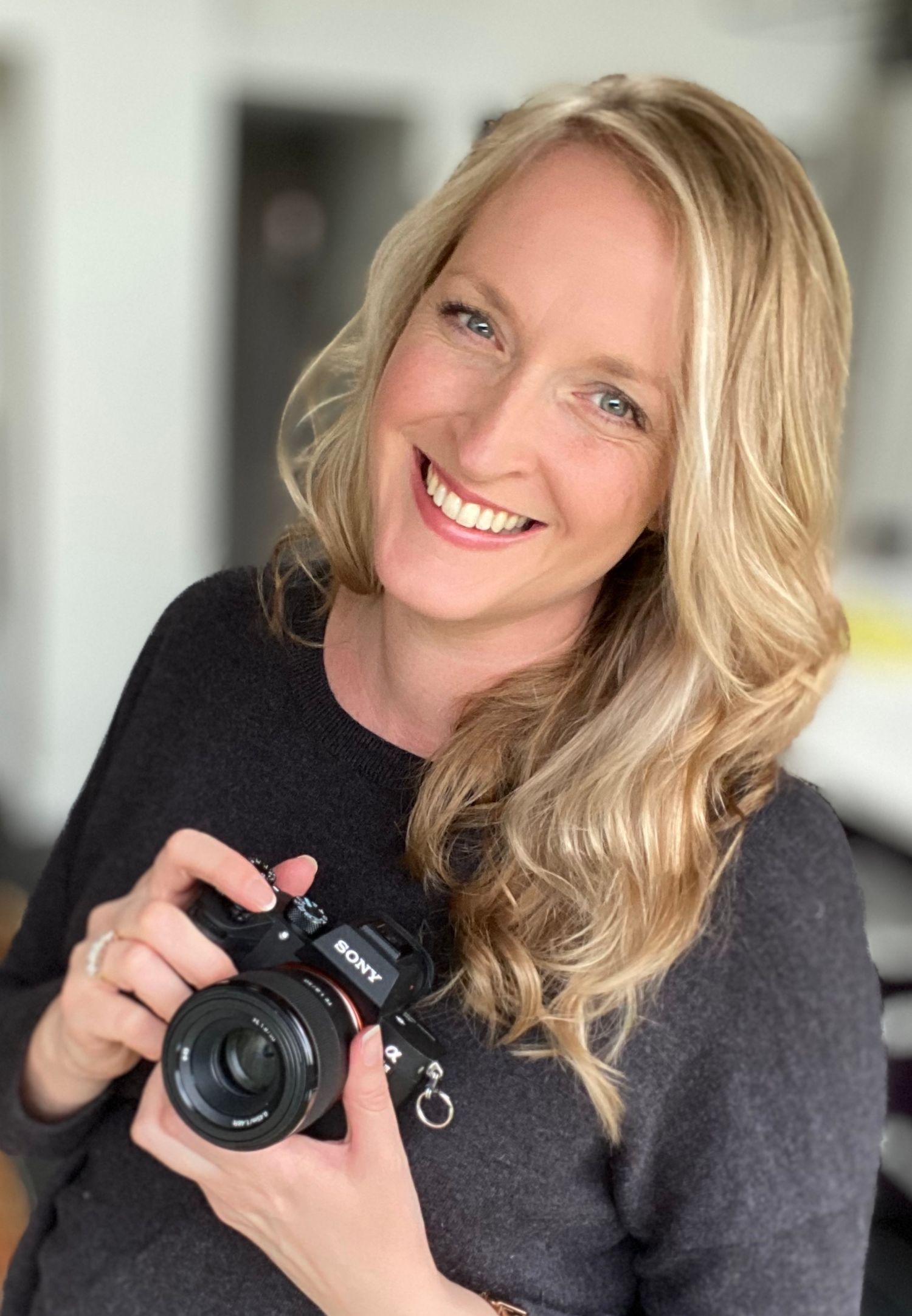 Wedding photographer holding camera and smiling behind the scenes during a wedding day