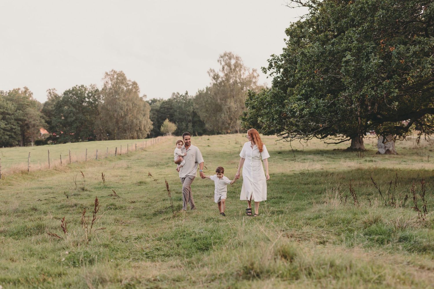 A family walks together through a serene pastoral field during golden hour in the countryside.