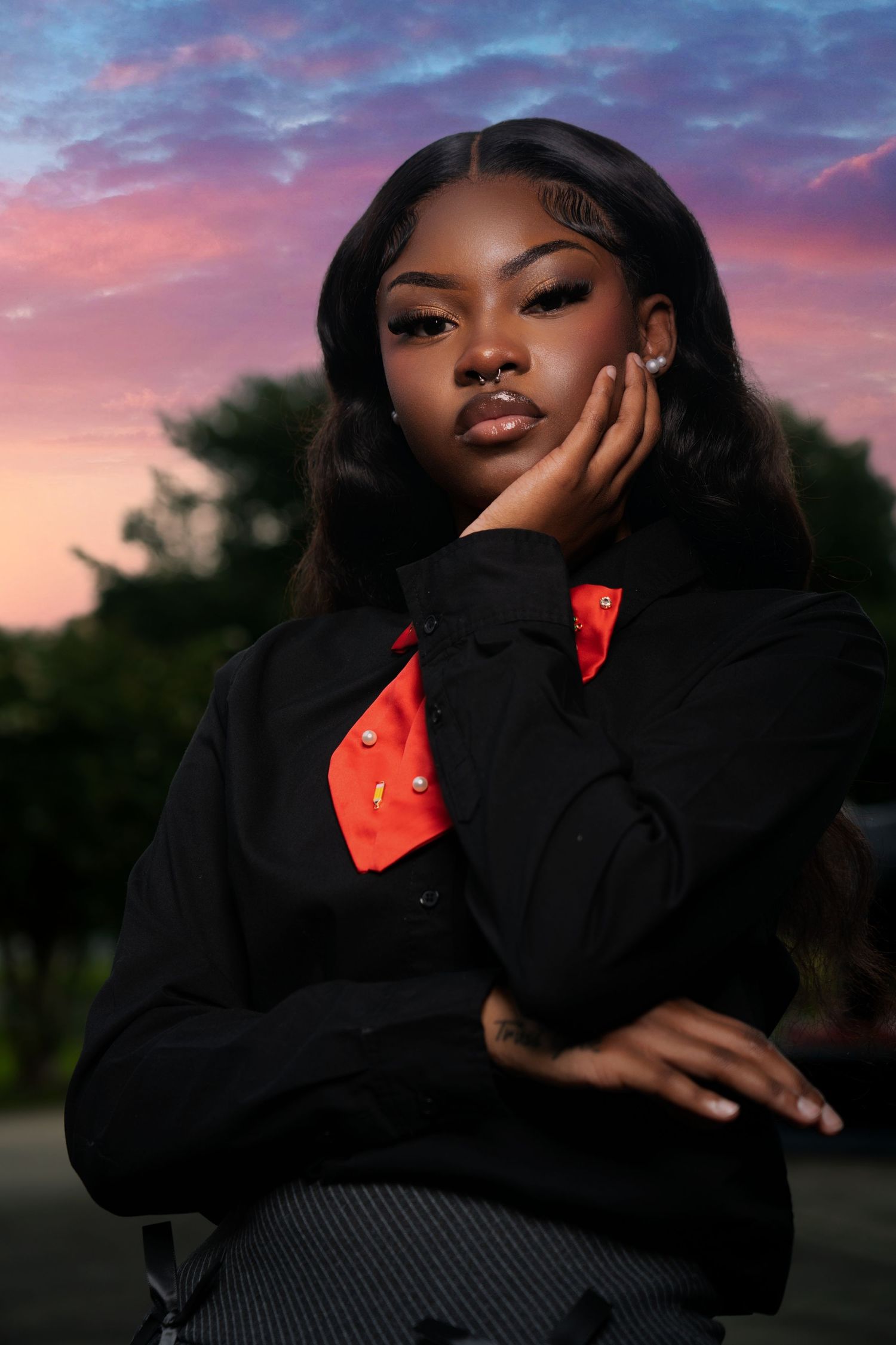 Fashion portrait against vibrant sunset sky with dramatic purple and pink clouds in background.