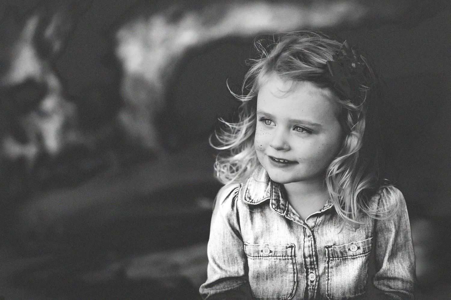Black and white portrait of child with windswept hair looking to the side.