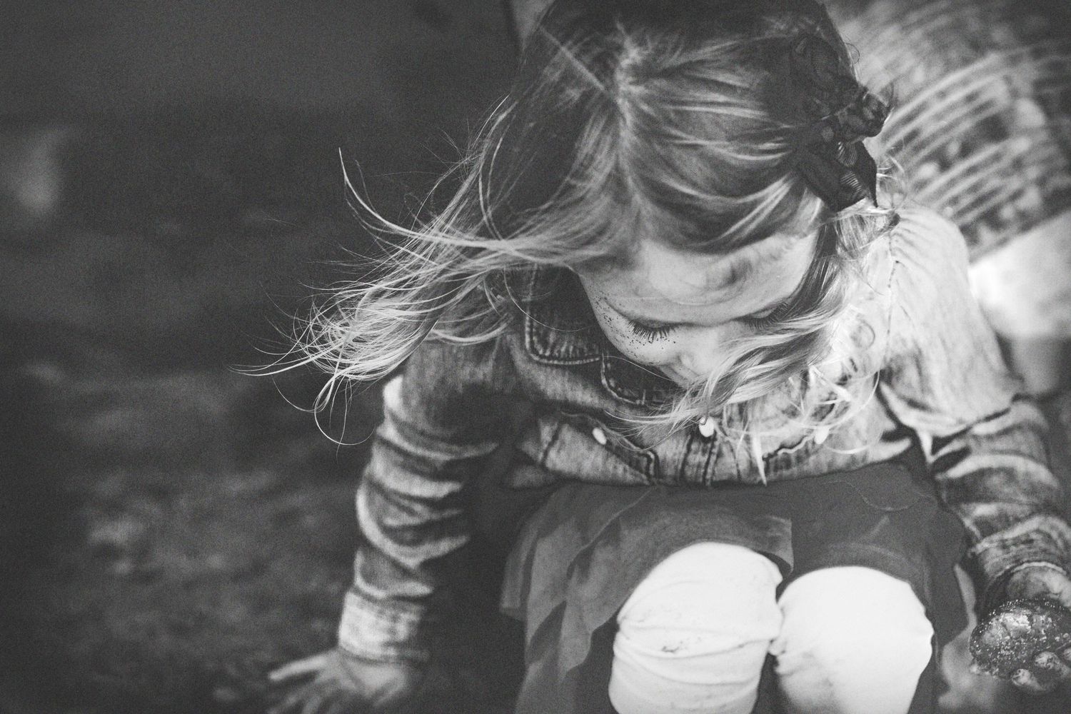 Black and white image of child in striped shirt looking down.