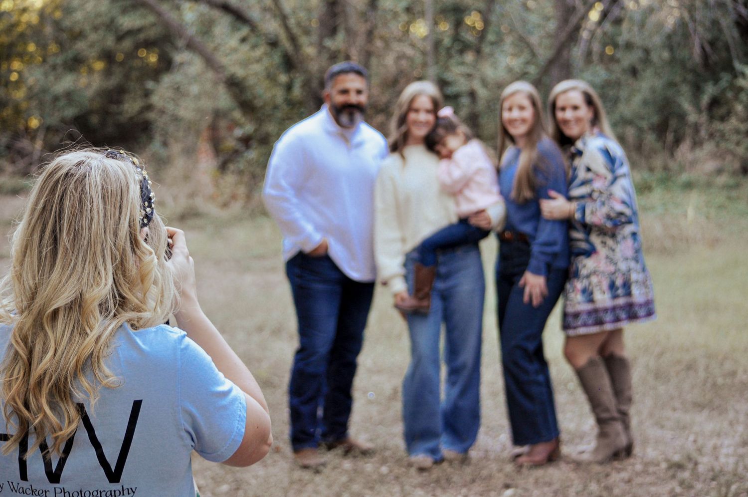 A group of people gather outdoors in a natural setting during golden hour for a casual photo session.