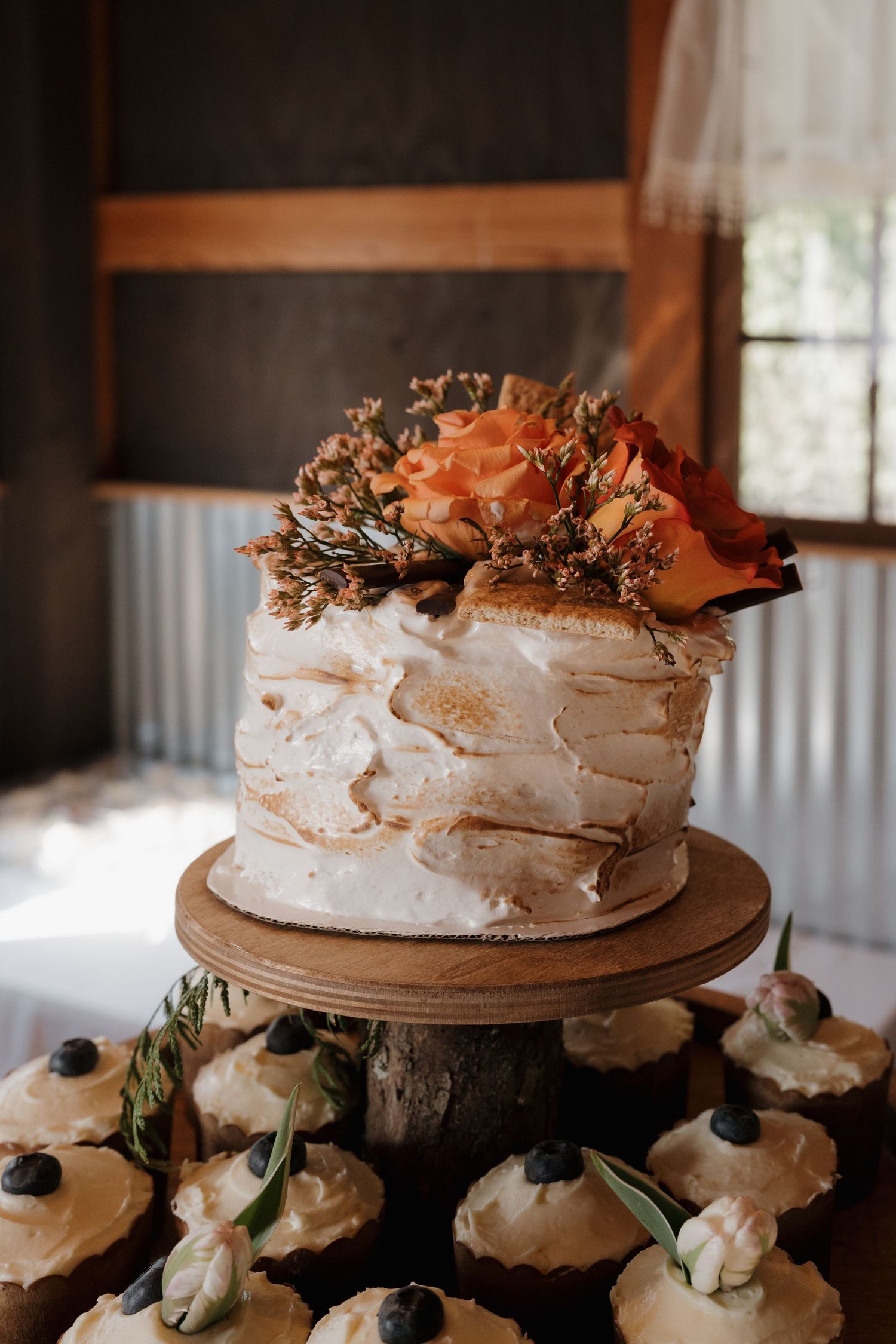 Rustic pavlova desserts with berries and floral decorations displayed on wooden cake stands at a wedding reception. Leavenworth, WA