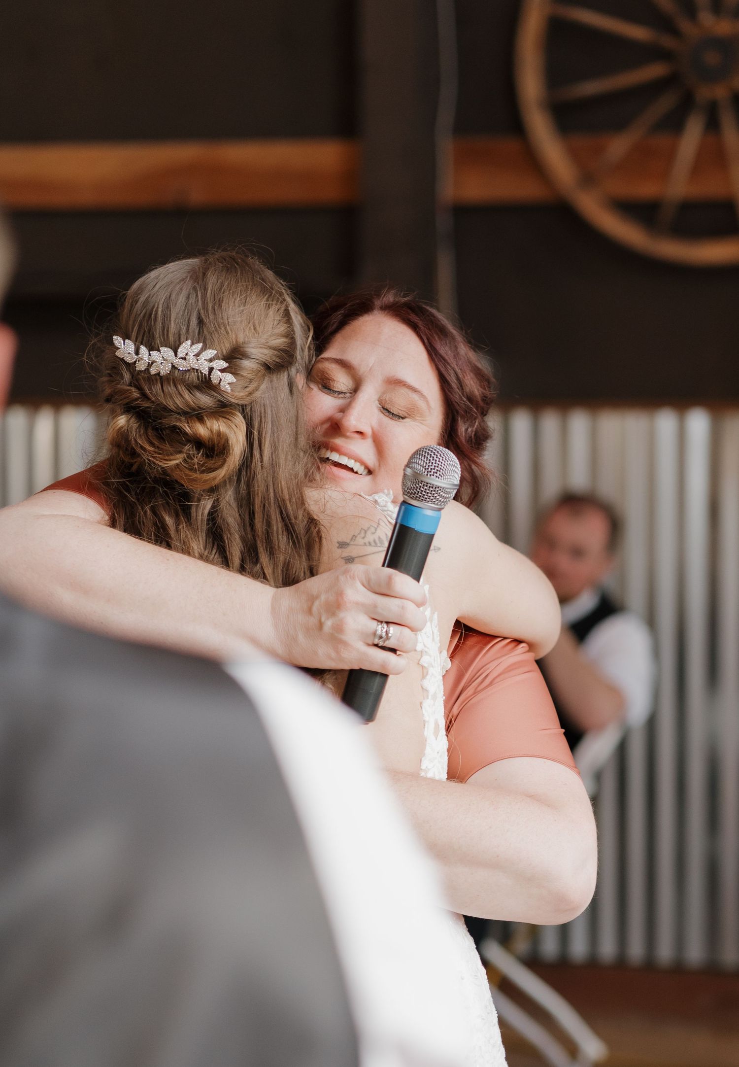 Two people in formal attire share an emotional embrace during what appears to be a wedding celebration. Leavenworth, WA