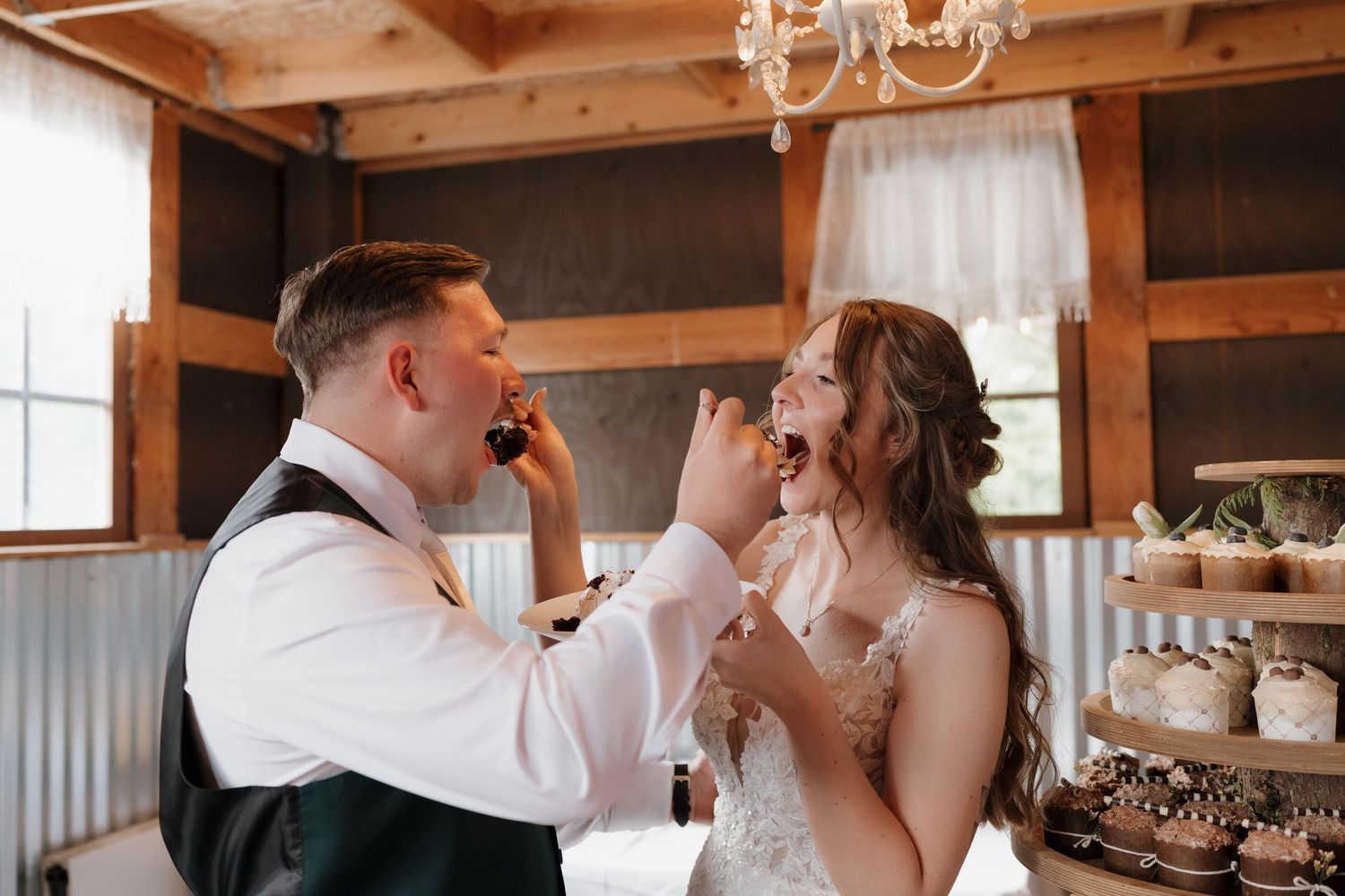 A rustic barn wedding venue with exposed wooden beams and a chandelier creates a warm, romantic atmosphere. Leavenworth, WA
