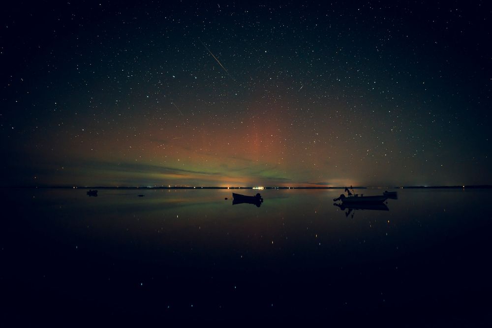 Nordlys fra Ålbæk landingsplads ud over Limfjorden hvor der ses både i silhuet.